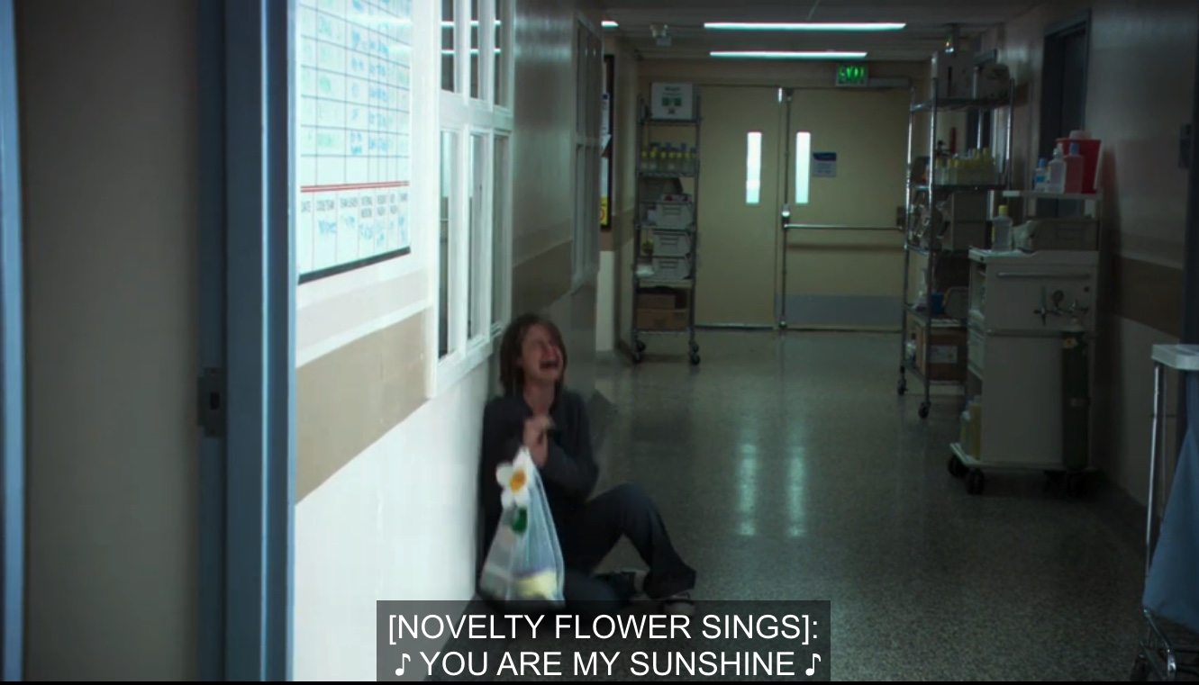 Alice in a hospital hallway sobbing while holding a sunshine toy