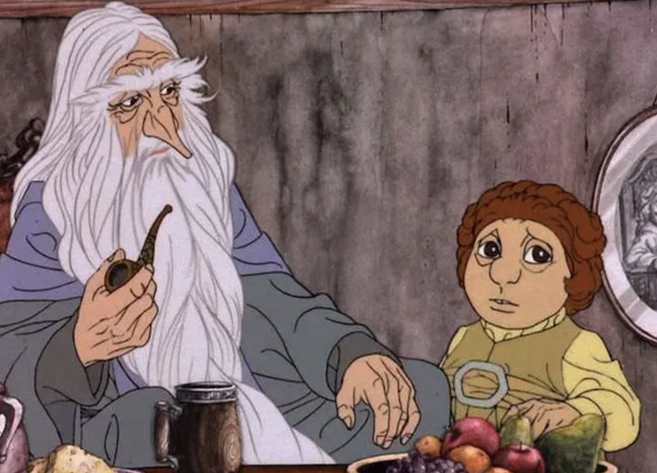 a still from the rankin bass animated hobbit with gandalf and bilbo sitting at table. gandalf has no hat and is holding a pipe
