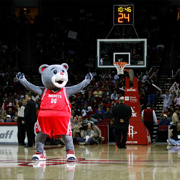Clutch Bear in a red Rockets basketball uniform on a basketball court, holding his arms out in victory