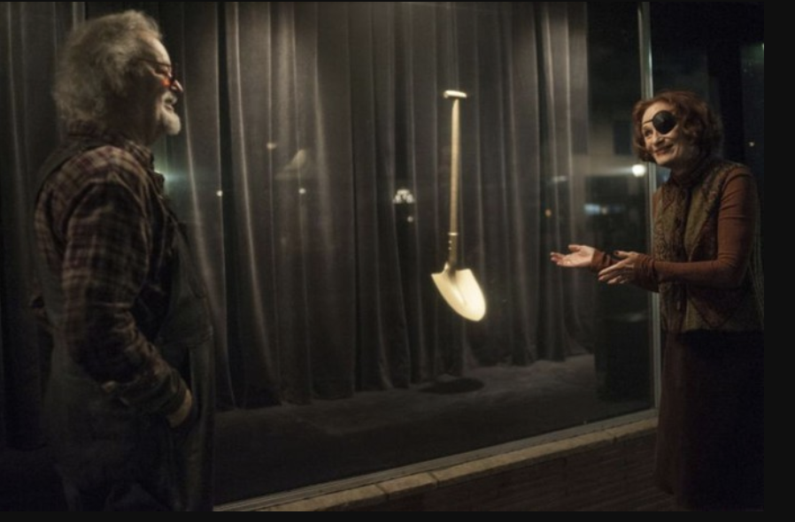 a woman in an eyepatch gestures toward a golden shovel to an old man in plaid on the tv show Twin Peaks