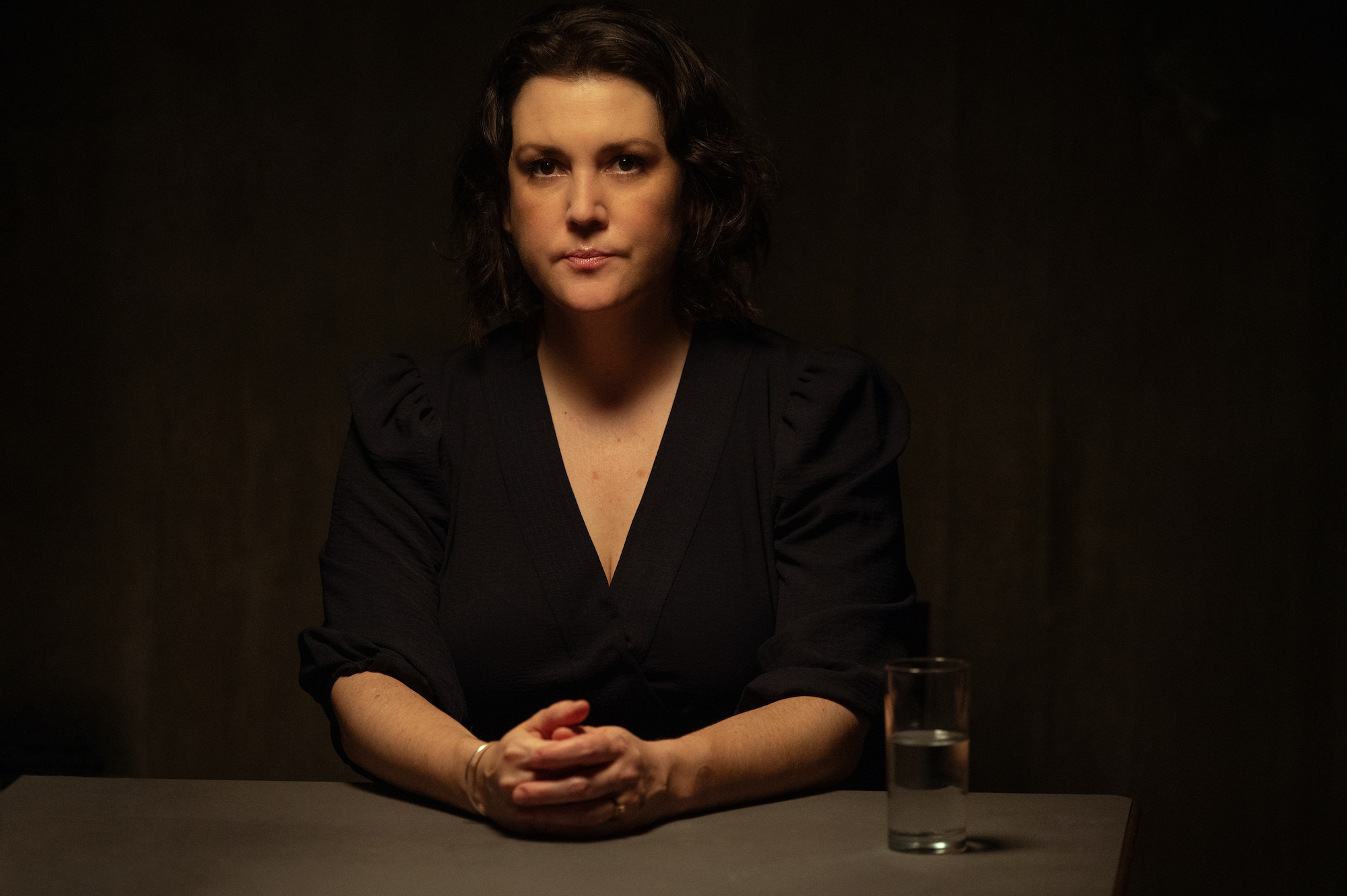 Yellowjackets Melanie Lynskey as Shauna in YELLOWJACKETS sits at a table and faces the camera. Season 2. Photo Credit: Kimberley French/SHOWTIME.