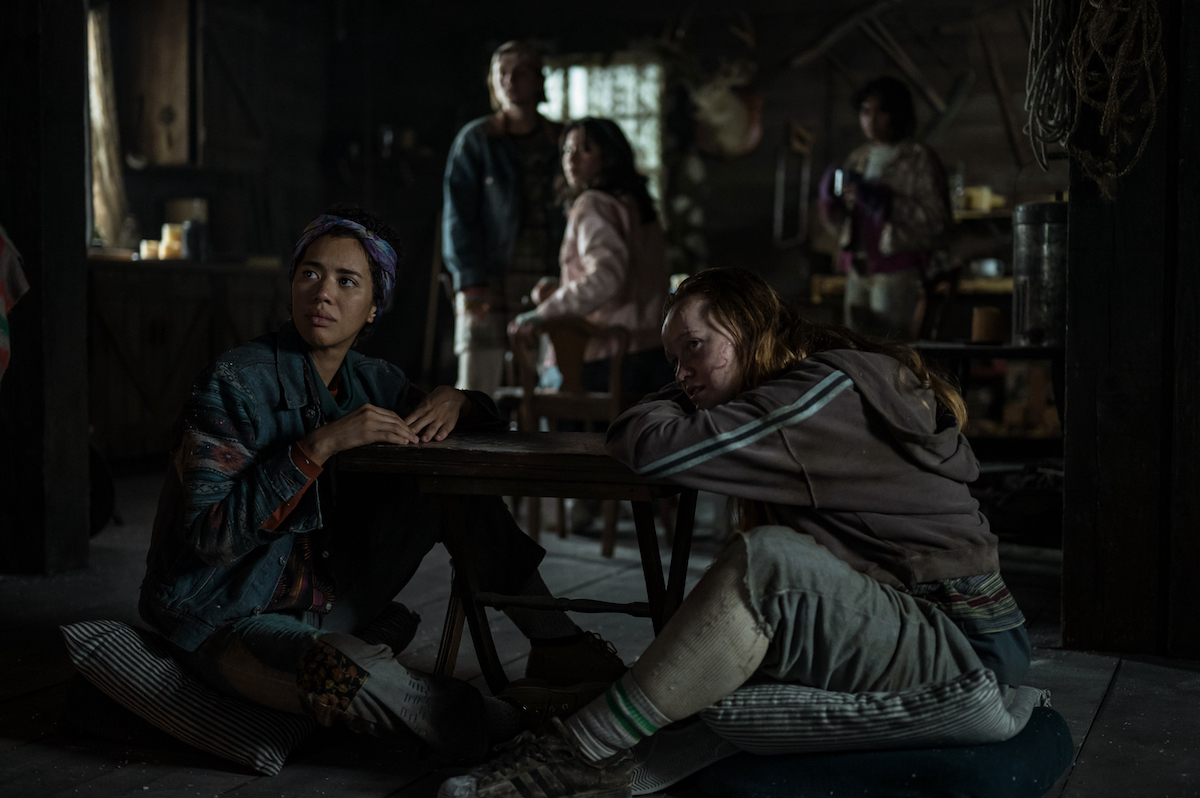 Yellowjackets (L-R): Jasmin Savoy Brown as Teen Taissa, Jenna Burgess as Teen Melissa, Mya Lowe as Teen Gen and Liv Hewson as Teen Van in YELLOWJACKETS Season 2 sit on the floor of a cabin. Photo Credit: Kailey Schwerman/SHOWTIME.
