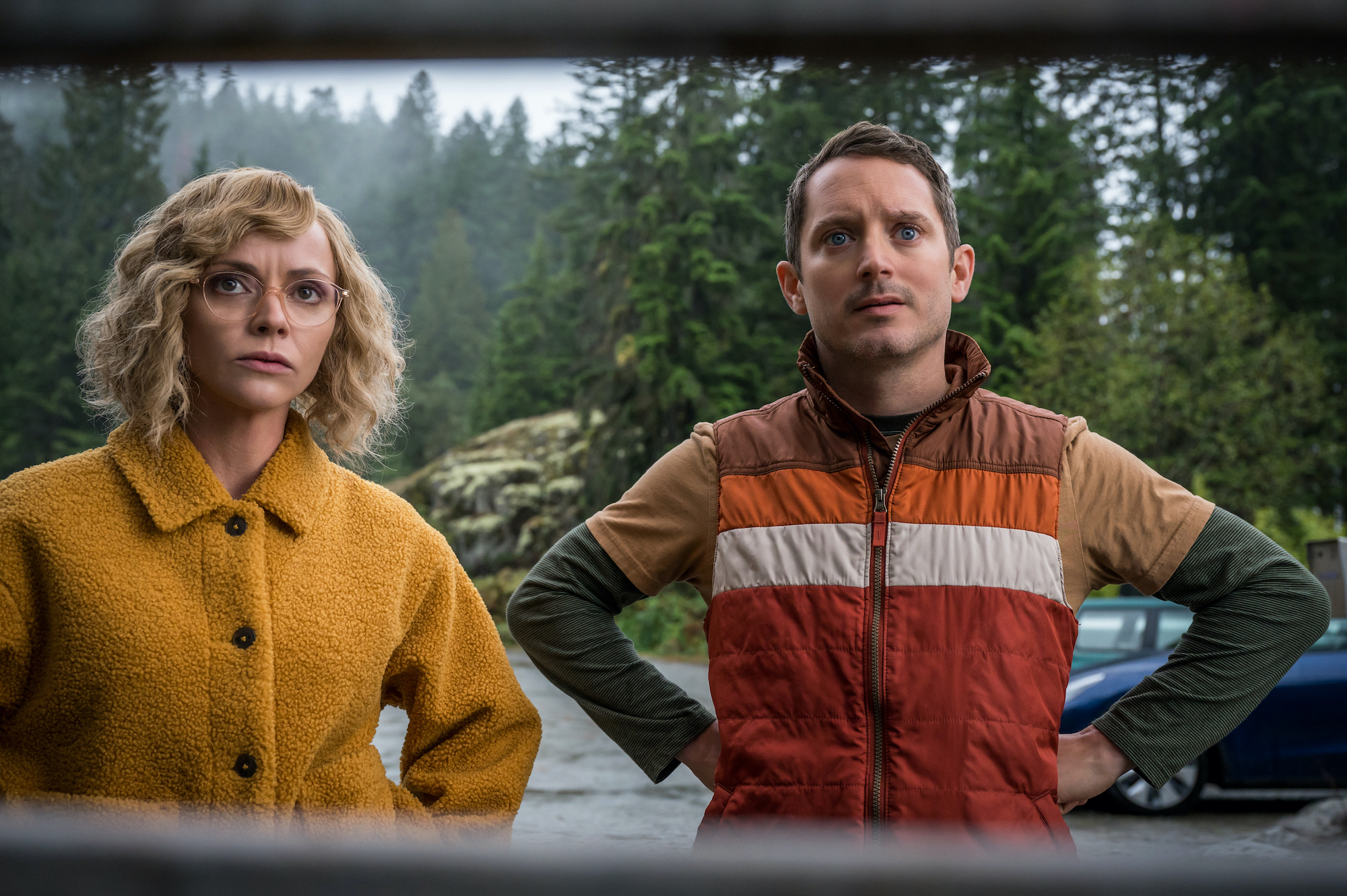 Yellowjackets - Season 2 (L-R): Christina Ricci as Misty and Elijah Wood as Walter in YELLOWJACKETS Season 2 stand looking at something in the woods. Photo Credit: Kailey Schwerman/SHOWTIME.