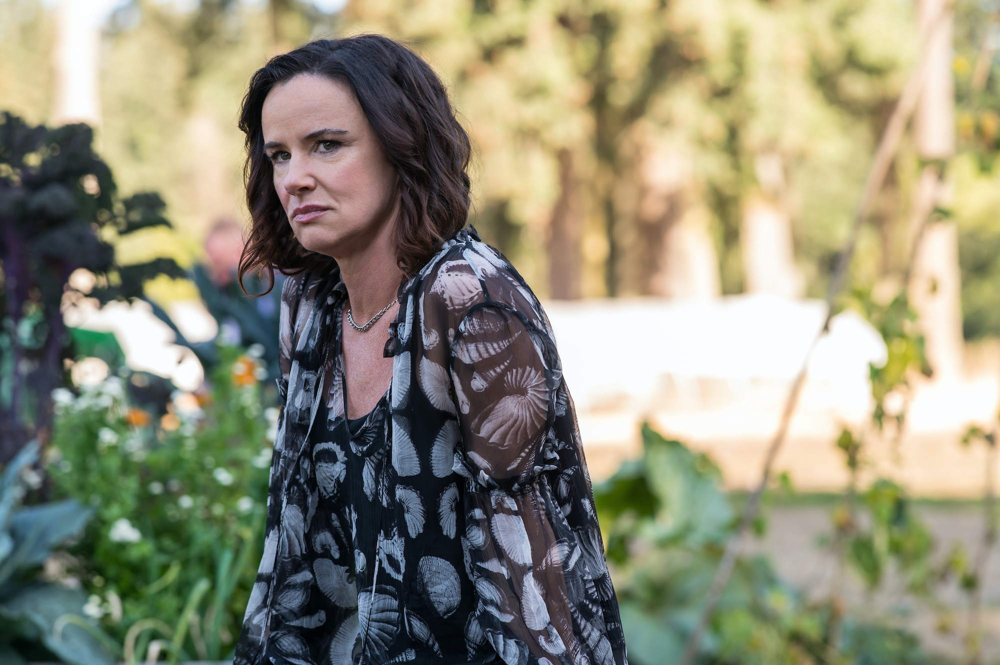 Yellowjackets - Season 2 Juliette Lewis as Natalie in YELLOWJACKETS S2 sits in a garden in a floral dress. Photo Credit: Kailey Schwerman/SHOWTIME.