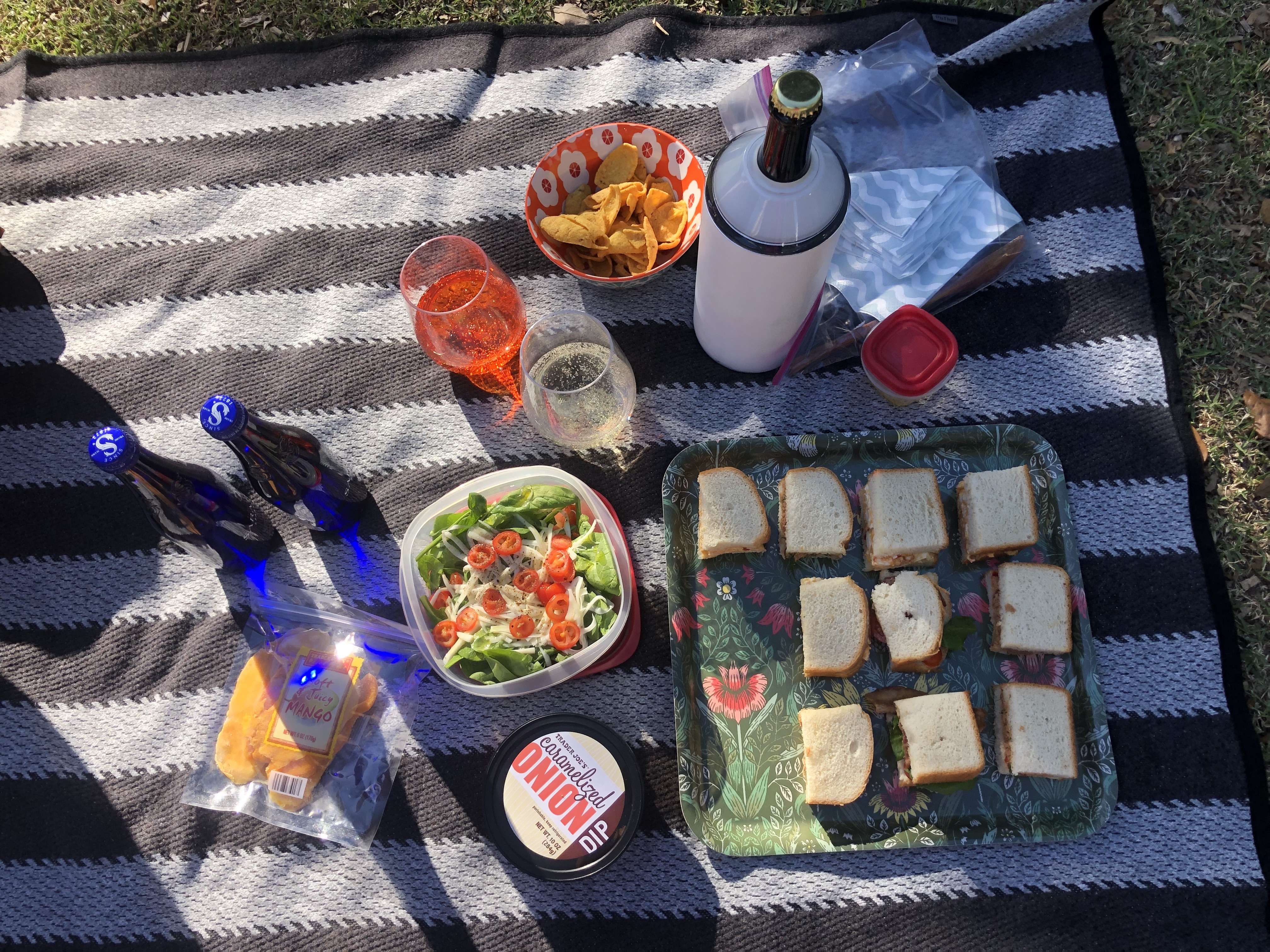 tiny sandwiches, salad, seltzer, wine, corn chips, caramelized onion dip, sliced mango