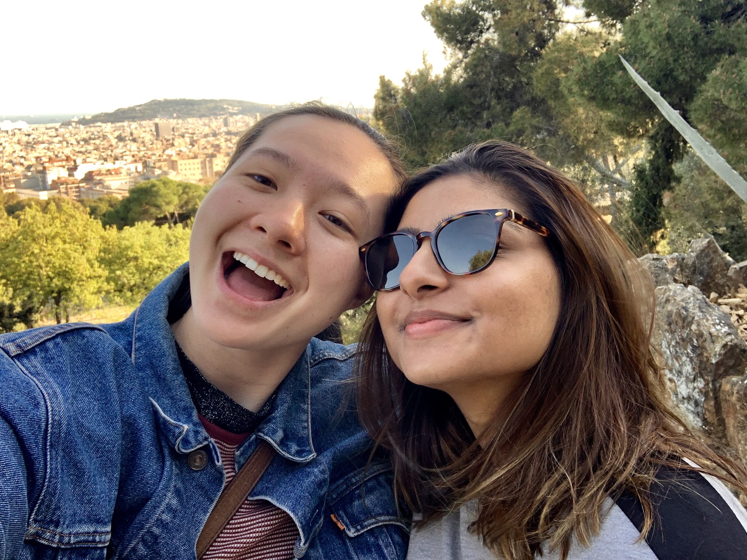 MR (left) and Ashni (right) are looking up at the camera. Ashni is wearing sunglasses and a gray sweater. MR is wearing a denim jacket.