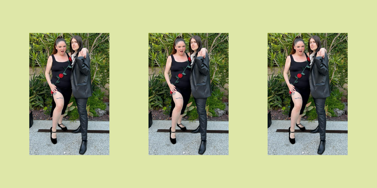 Meg Stalter in a black dress with a rose design with her partner, who is in a suit