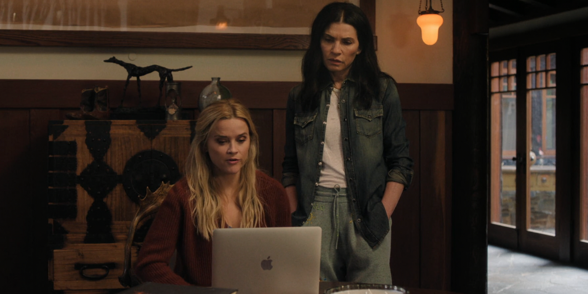 Reese Witherspoon looking at her laptop and Julianna Margulies standing looking over her shoulder in