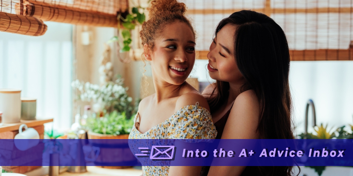 a young happy lesbian couple holds each other in a kitchen. text reads 