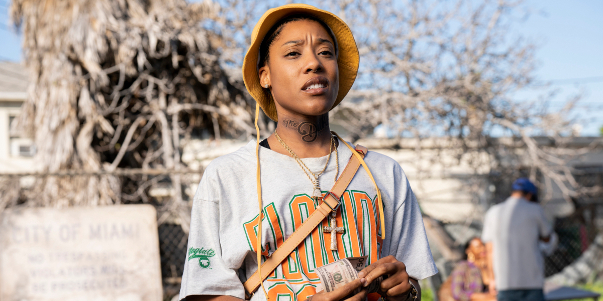 Chastity counts her money. She's wearing a Florida A&M t-shirt and a crossbody bag with a matching bucket cap.