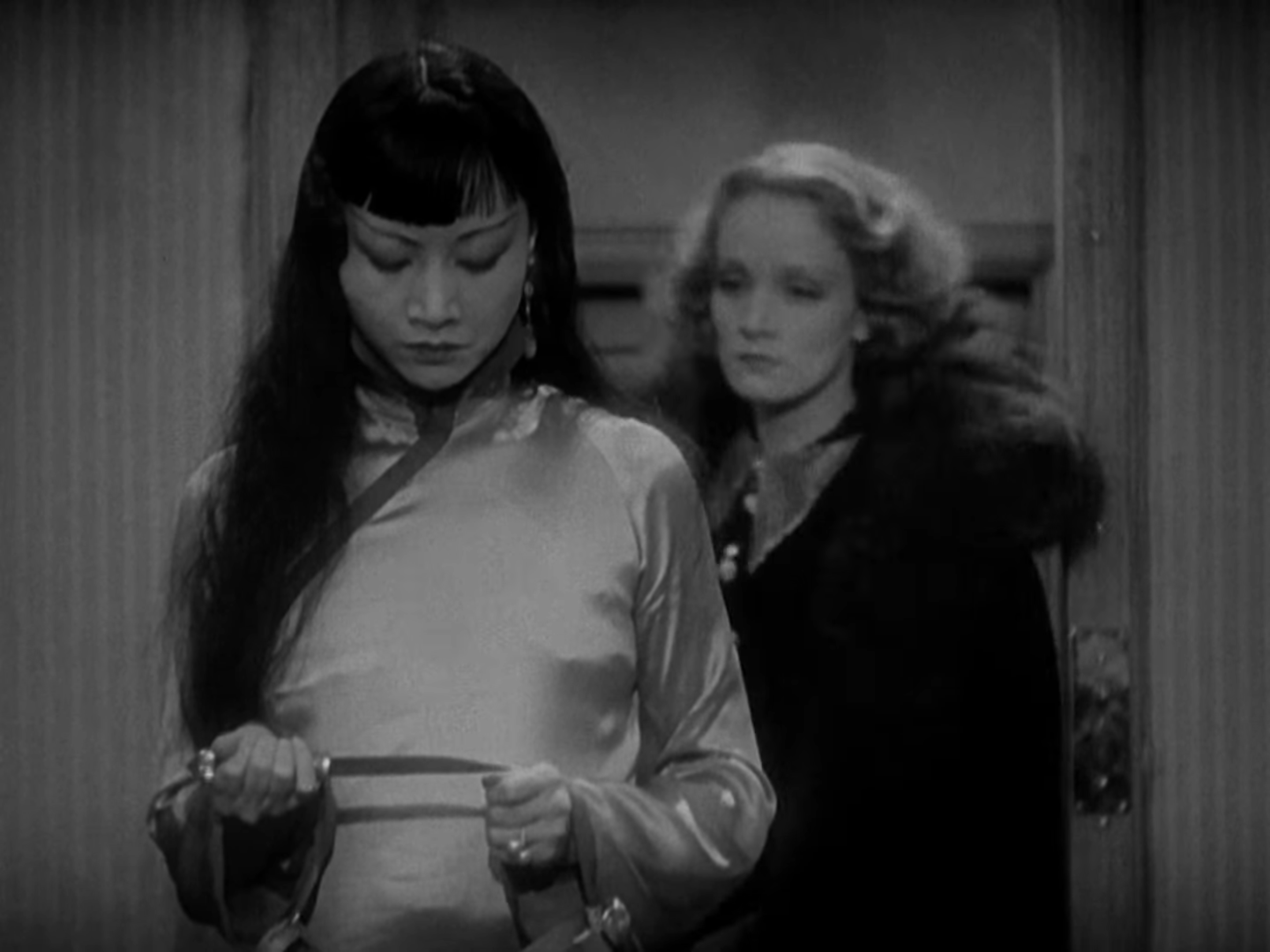 Anna May Wong grips a knife as Marlene Dietrich approaches behind her
