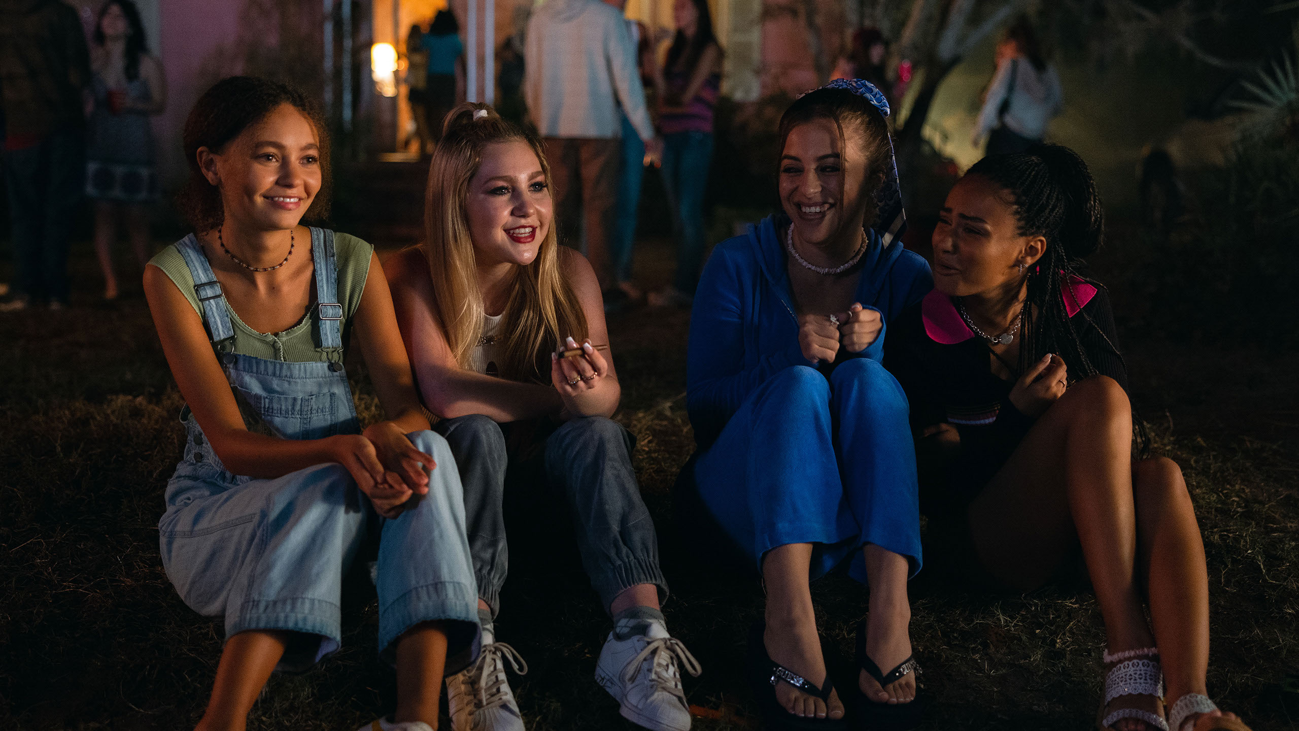 Four teenage girls sit next to each other smiling.