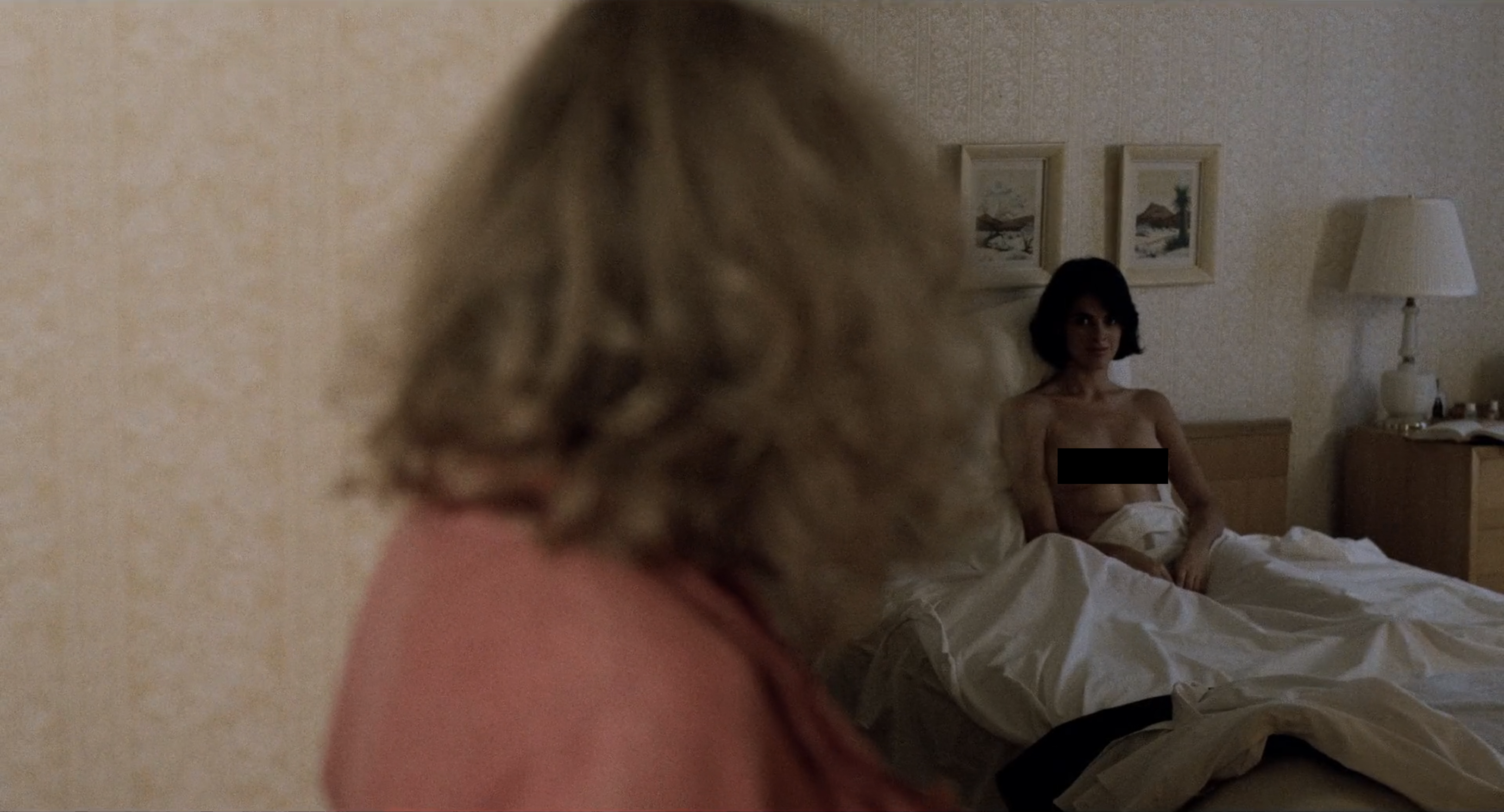 Desert Hearts sex scene: Vivian turns her head to see Cay in bed topless (a black rectangle is censoring her chest)