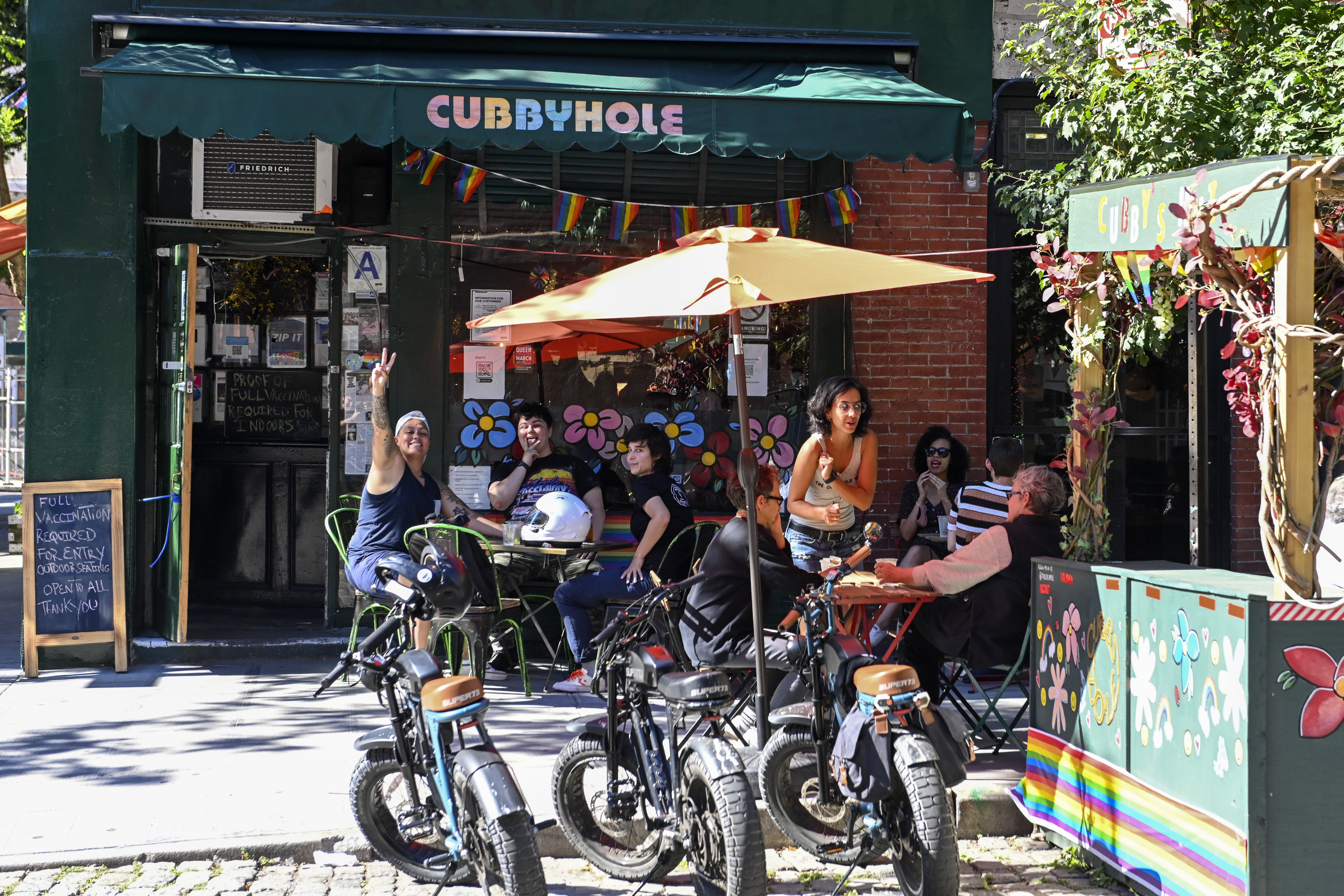 NEW YORK, NEW YORK - JUNE 17: Customers pose and make hand gestures outside Cubbyhole, a well known lesbian & gay bar, in the West Village on June 17, 2021 in New York City. On May 19, 2021 New York Governor Andrew Cuomo lifted all coronavirus pandemic restrictions paving the way for most Pride month events to resume normally. New York City Pride weekend will be June 25th-27th.