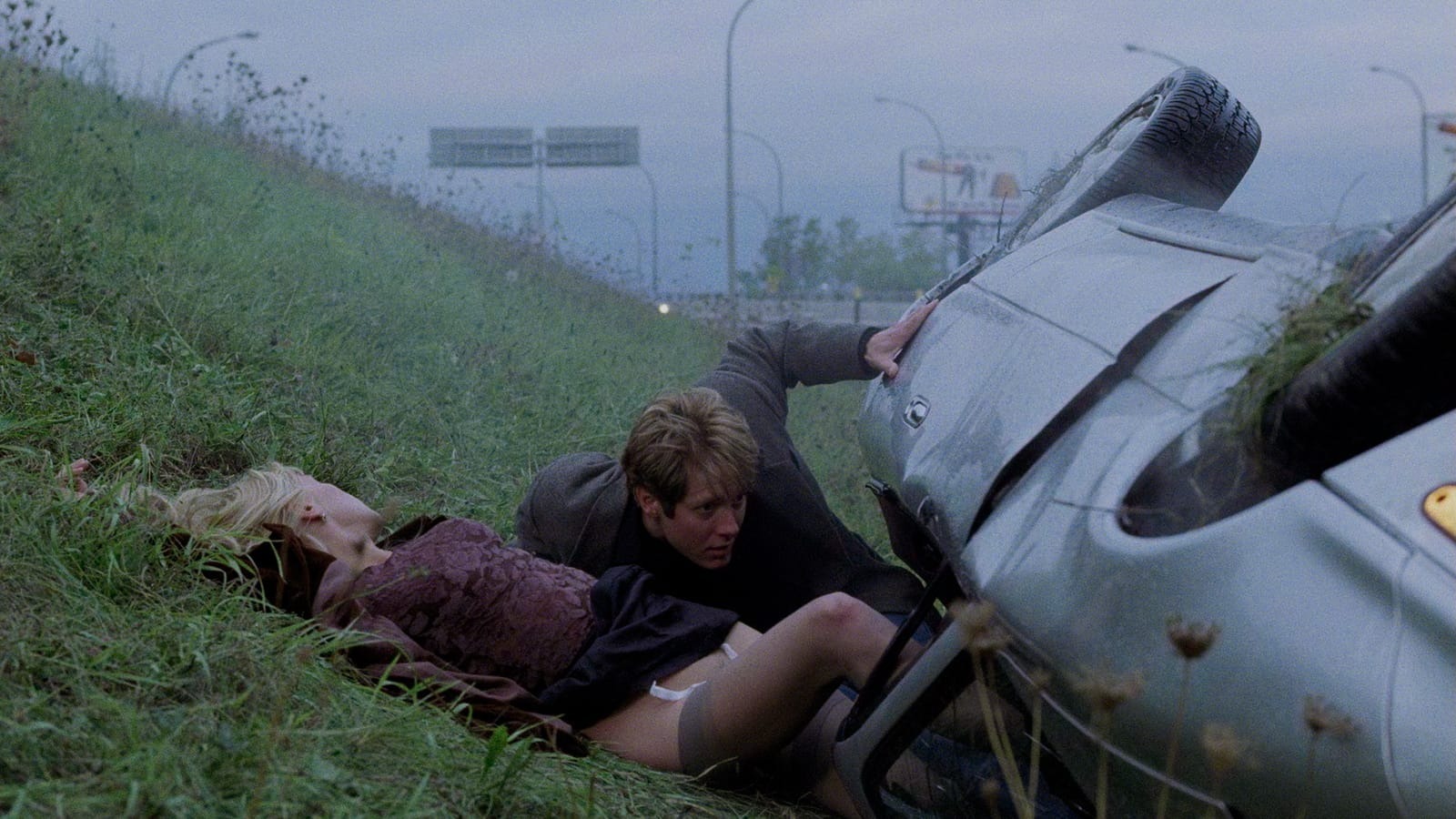 James Spader and Deborah Kara Unger lie by a crashed car in Crash