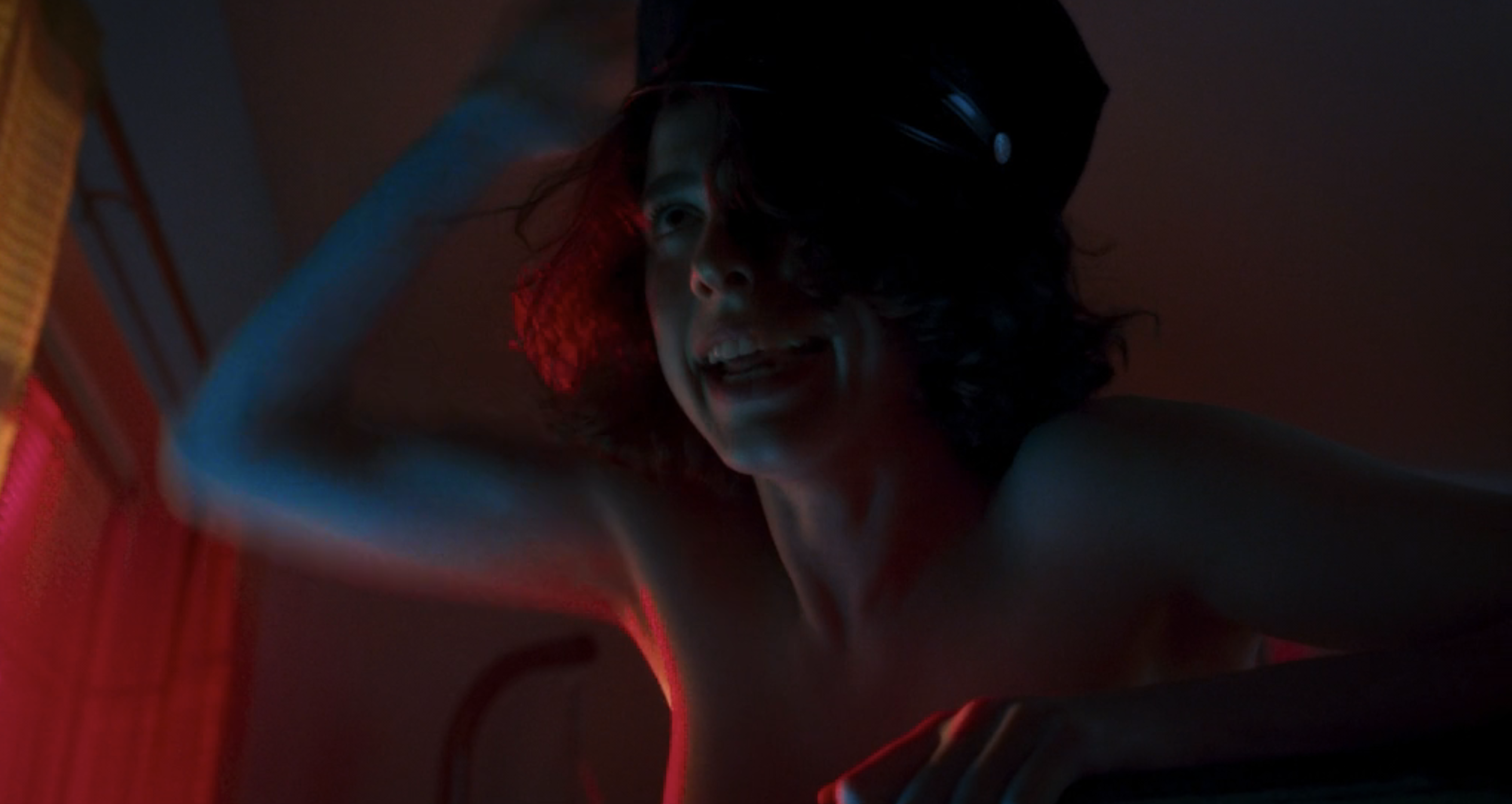 Jamie putting a cop hat on while having sex in Drive-Away Dolls