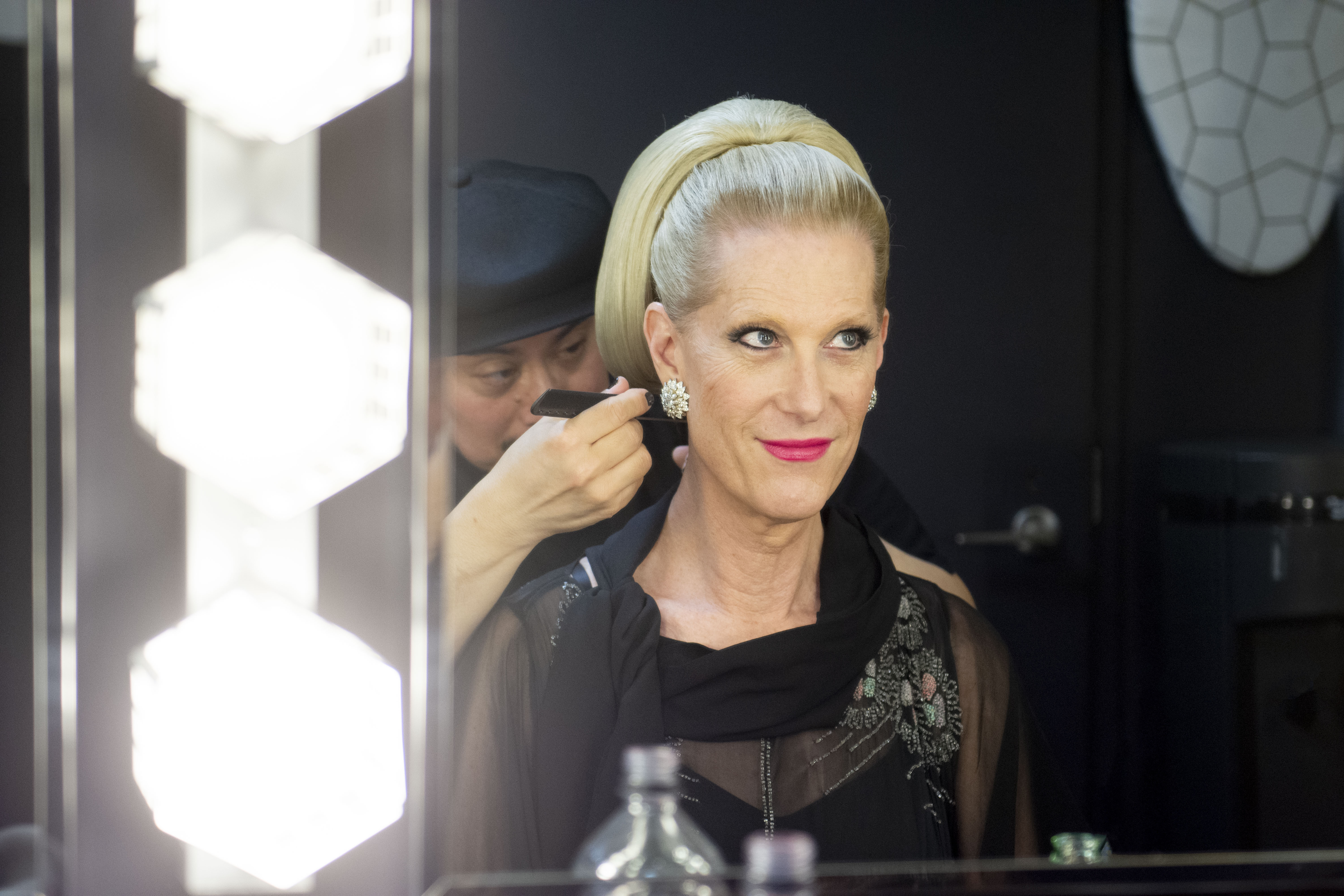 Justin Vivian Bond looks in a mirror and smiles as they get their hair done.