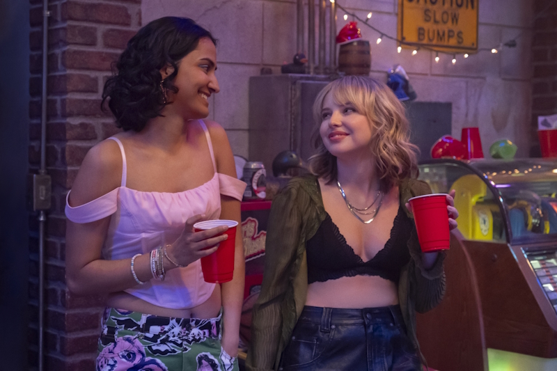 The Sex Lives of College Girls season three: Bela and her advisee, Taylor, have fun together at a fraternity party. They are looking at each other while holding red solo cups. 