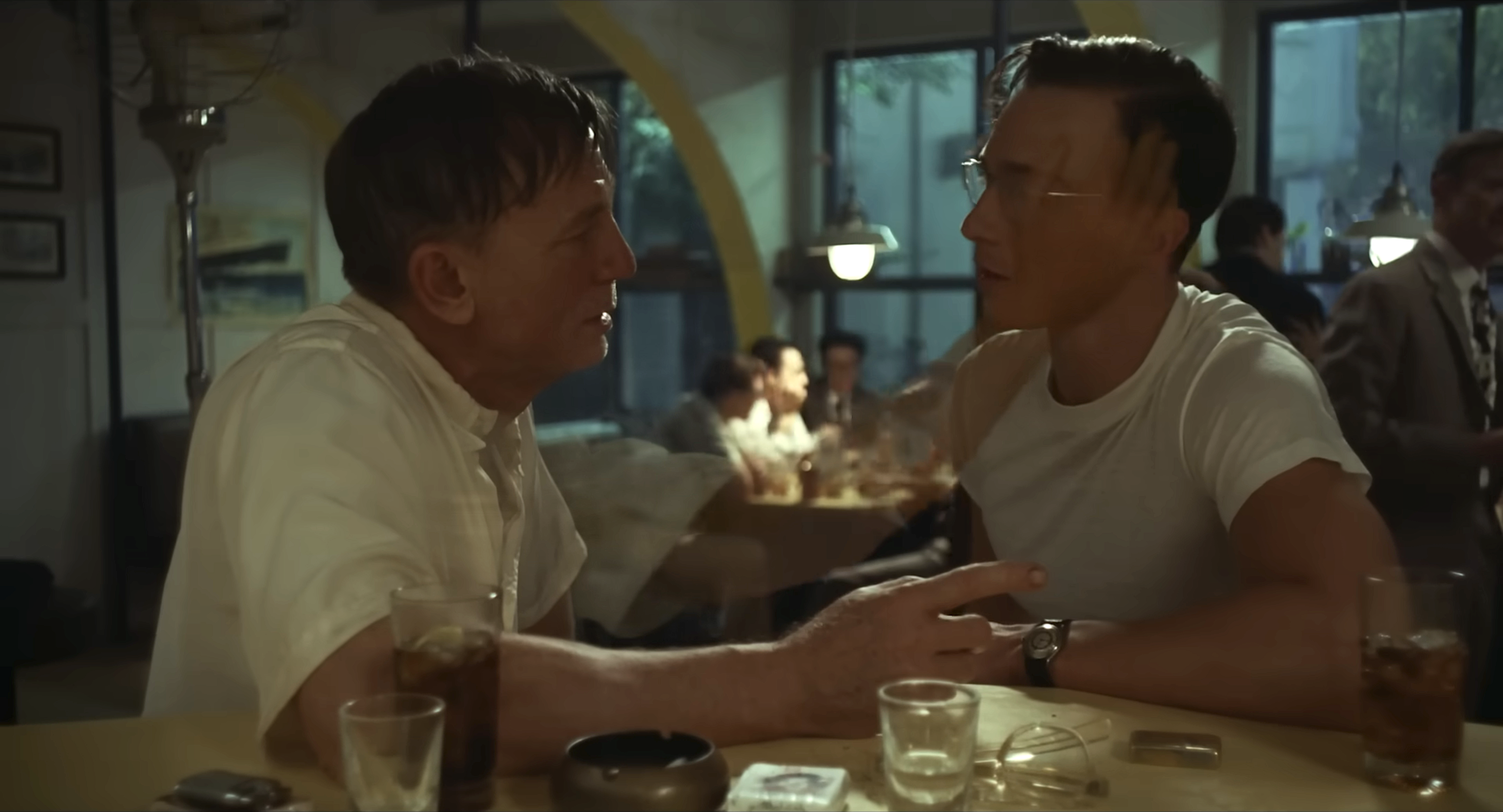 Daniel Craig talks to Drew Starkey at a bar, a phantom hand floating up to touch his face.
