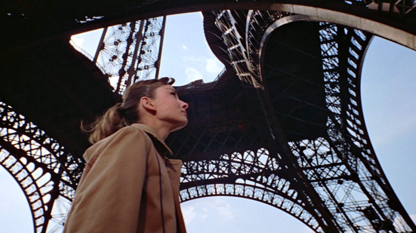 Audrey Hepburn looks up at the Eiffel Tower.