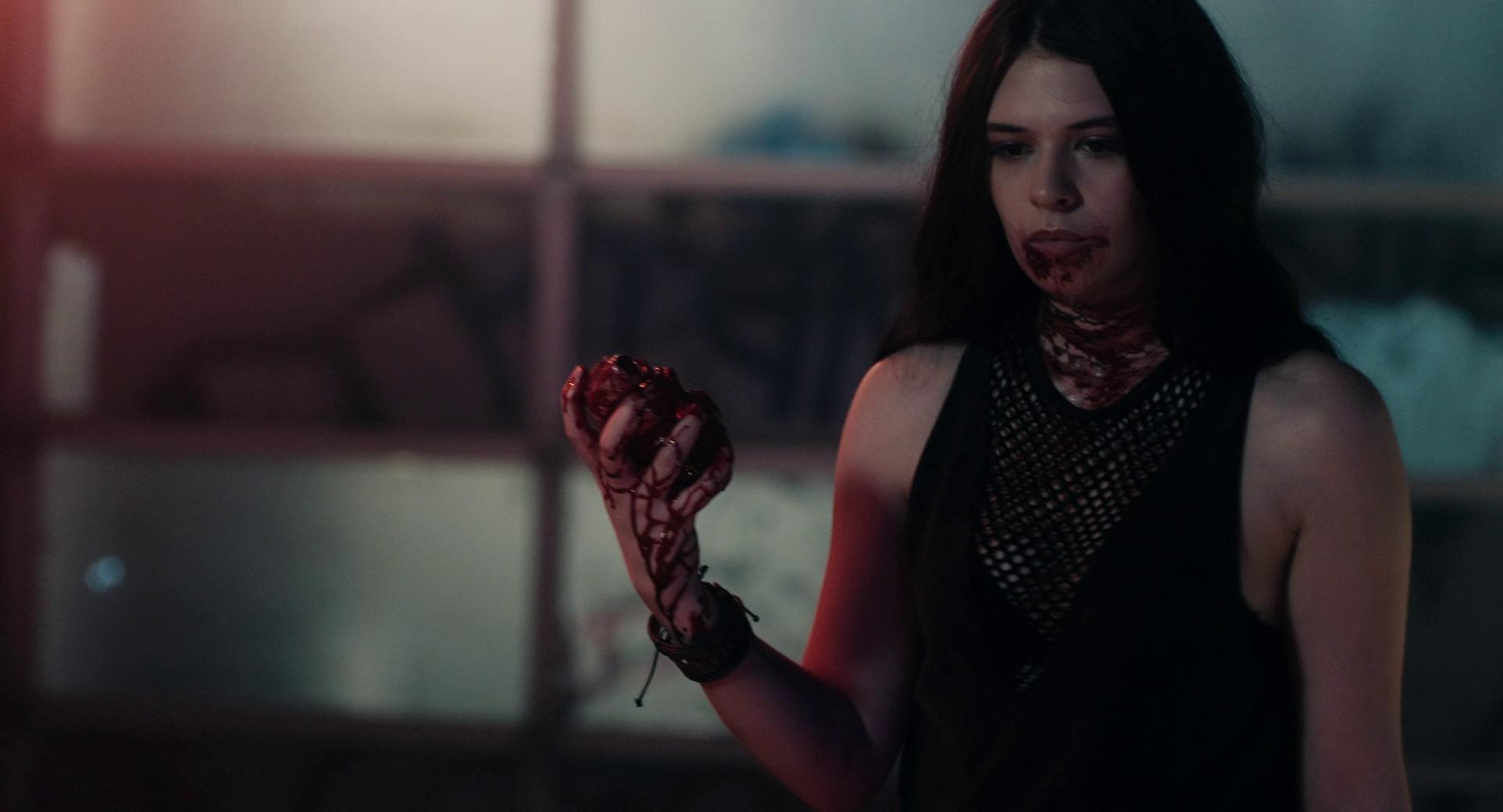 Nicole Maines holds a heart with blood on her mouth