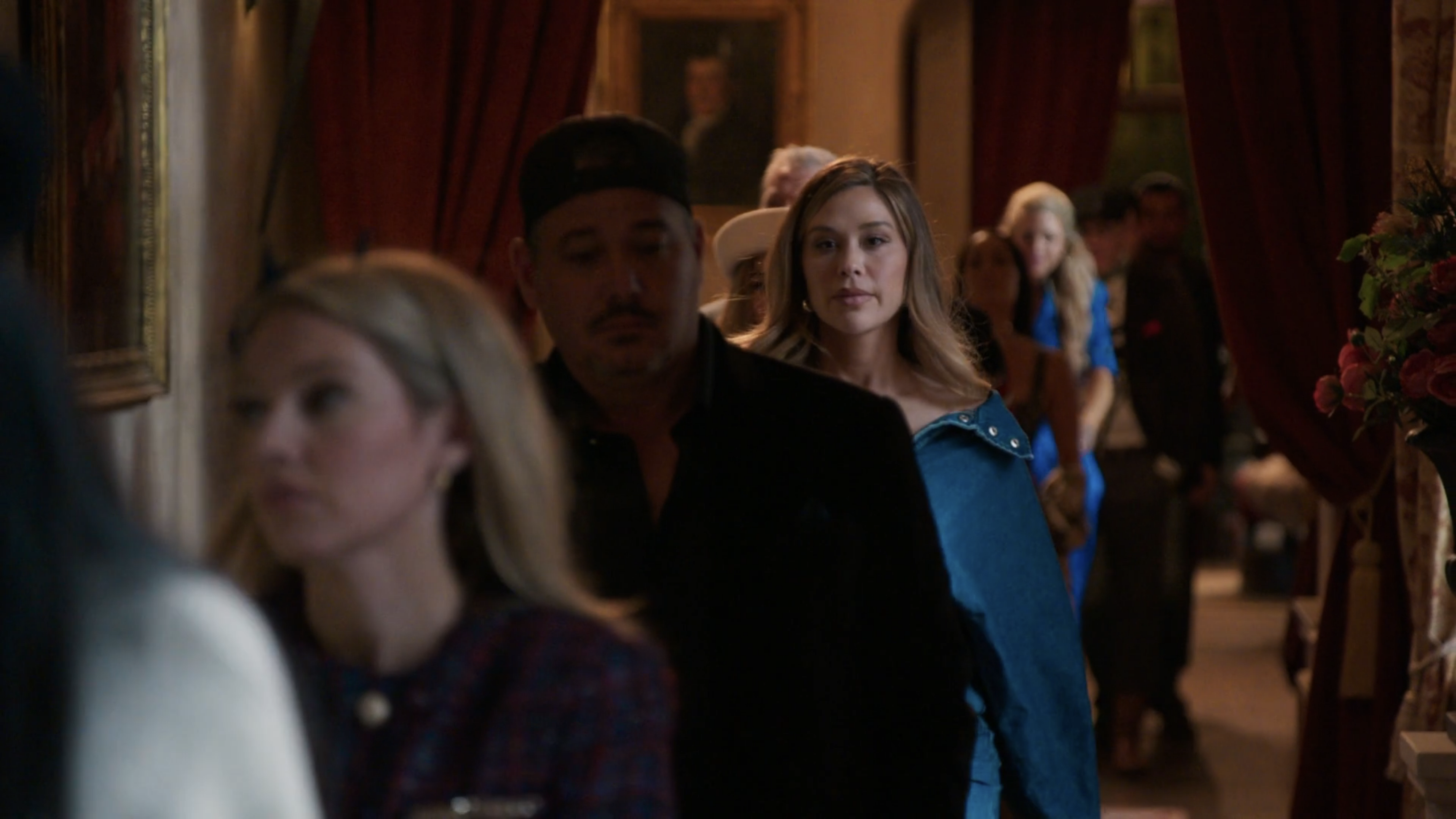 Gabby walks to the roundtable behind Rob in a boxy denim dress