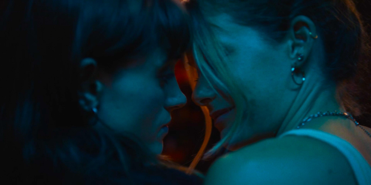 Two young women dance with their faces close together in a bar