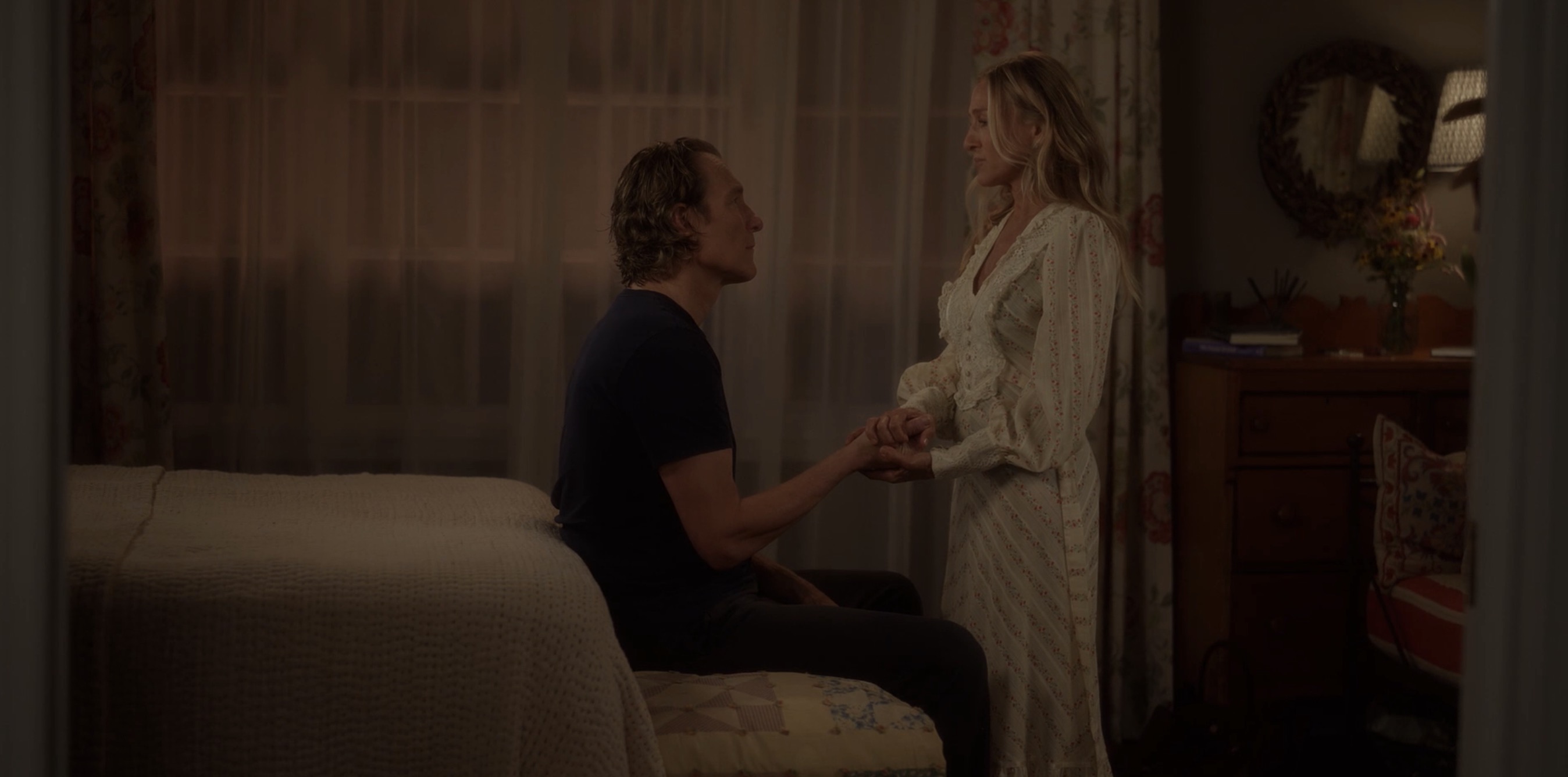 aidan holding carrie's hands while he sits on the bed