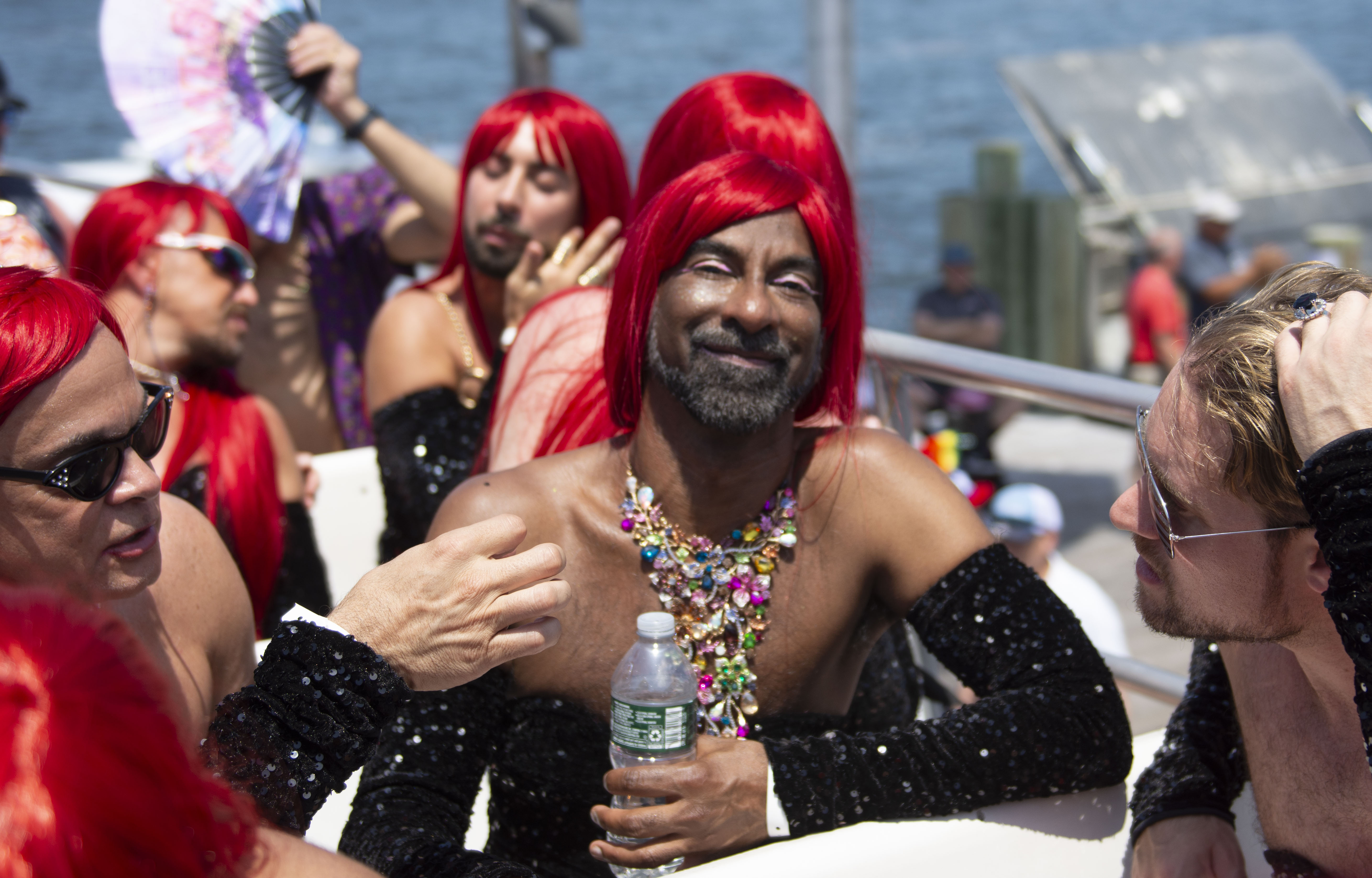 attendees of the 50th invasion of the pines wear red wigs on the ferry