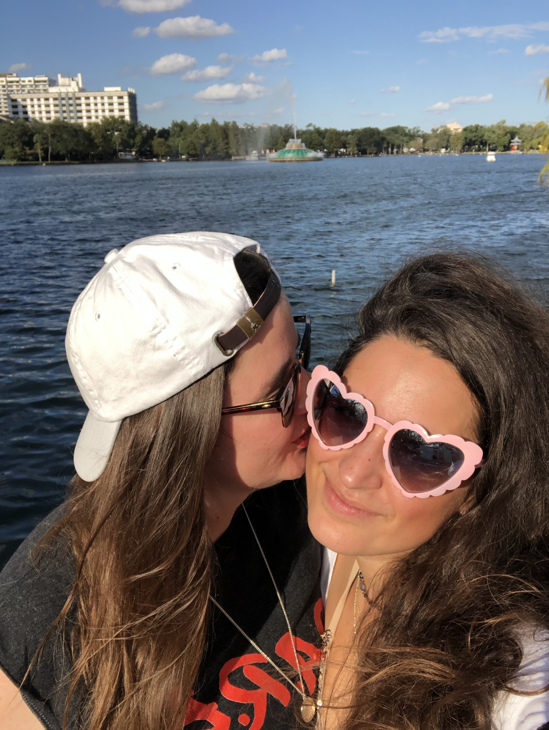 Kristen kissing Kayla's face in front of a lake