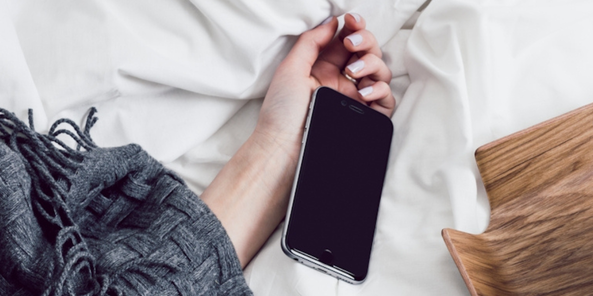 a hand on a phone in bed