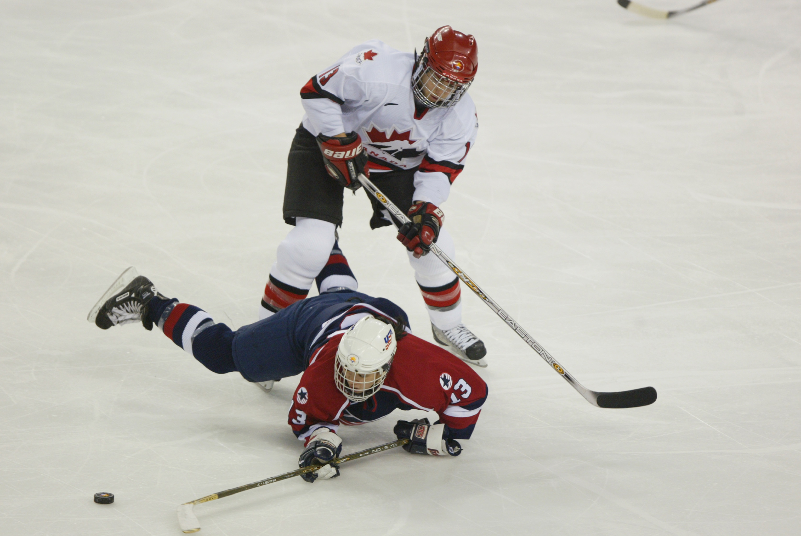 SALT LAKE CITY - FEBRUARY 21: Forward Caroline Ouellette #13 of Canada knocks down forward Julie Chu #13 of the USA as she tries to play the puck during the womens ice hockey gold medal game on February 21, 2002 at the Salt Lake City Winter Olympic at the E Center in Salt Lake City, Utah. (Photo by Robert Laberge/Getty Images)
