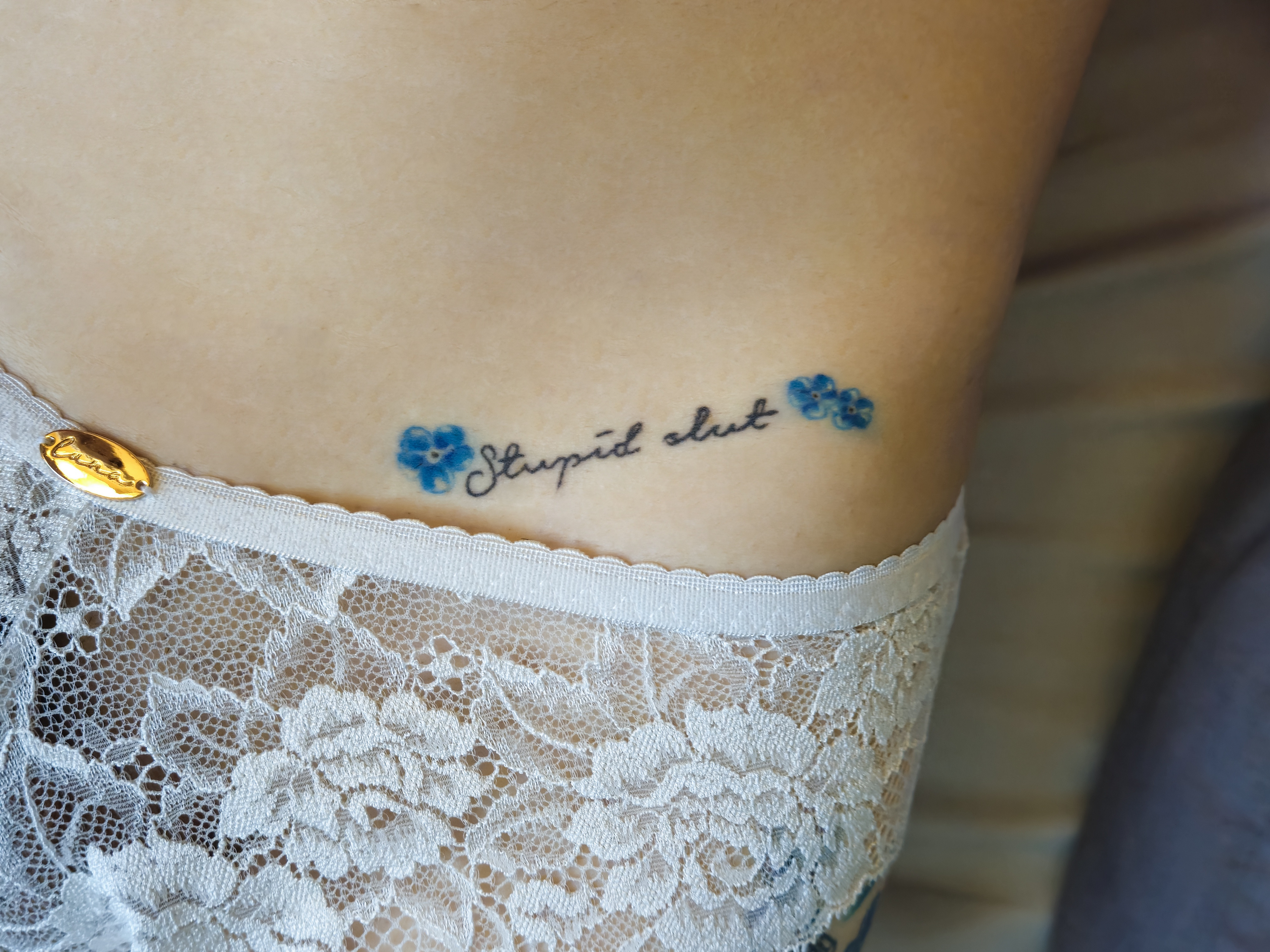 a body with the words stupid slut tattooed on