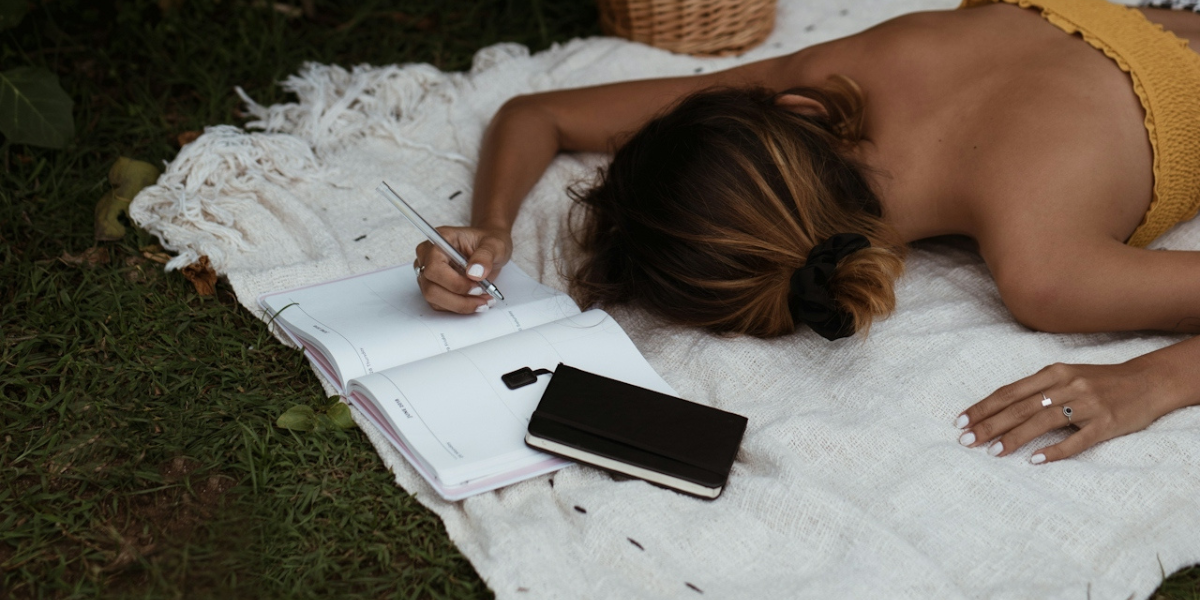 a woman writing in a journal while laying down