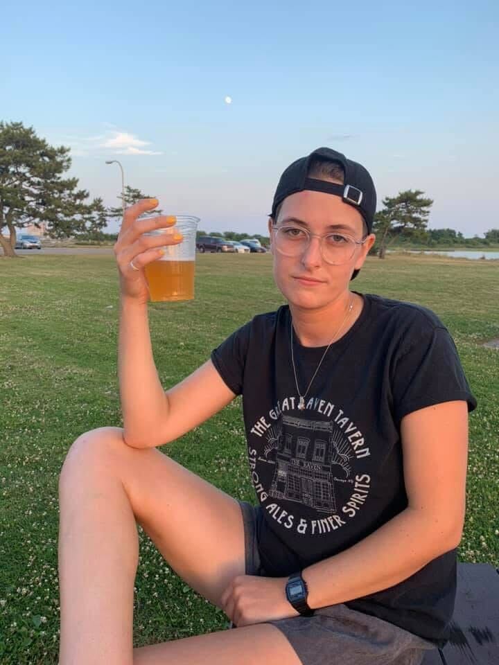 Motti in a field wiht a beer and a backwards hat
