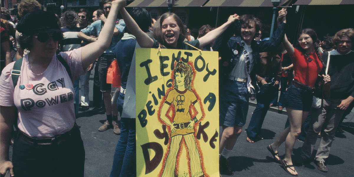 A woman holding a placard which reads 'I Enjoy Being a Dyke' during an LGBT parade through New York City on Christopher Street Gay Liberation Day 1971. (Photo by Yigal Mann/Pix/Michael Ochs Archives/Getty Images)