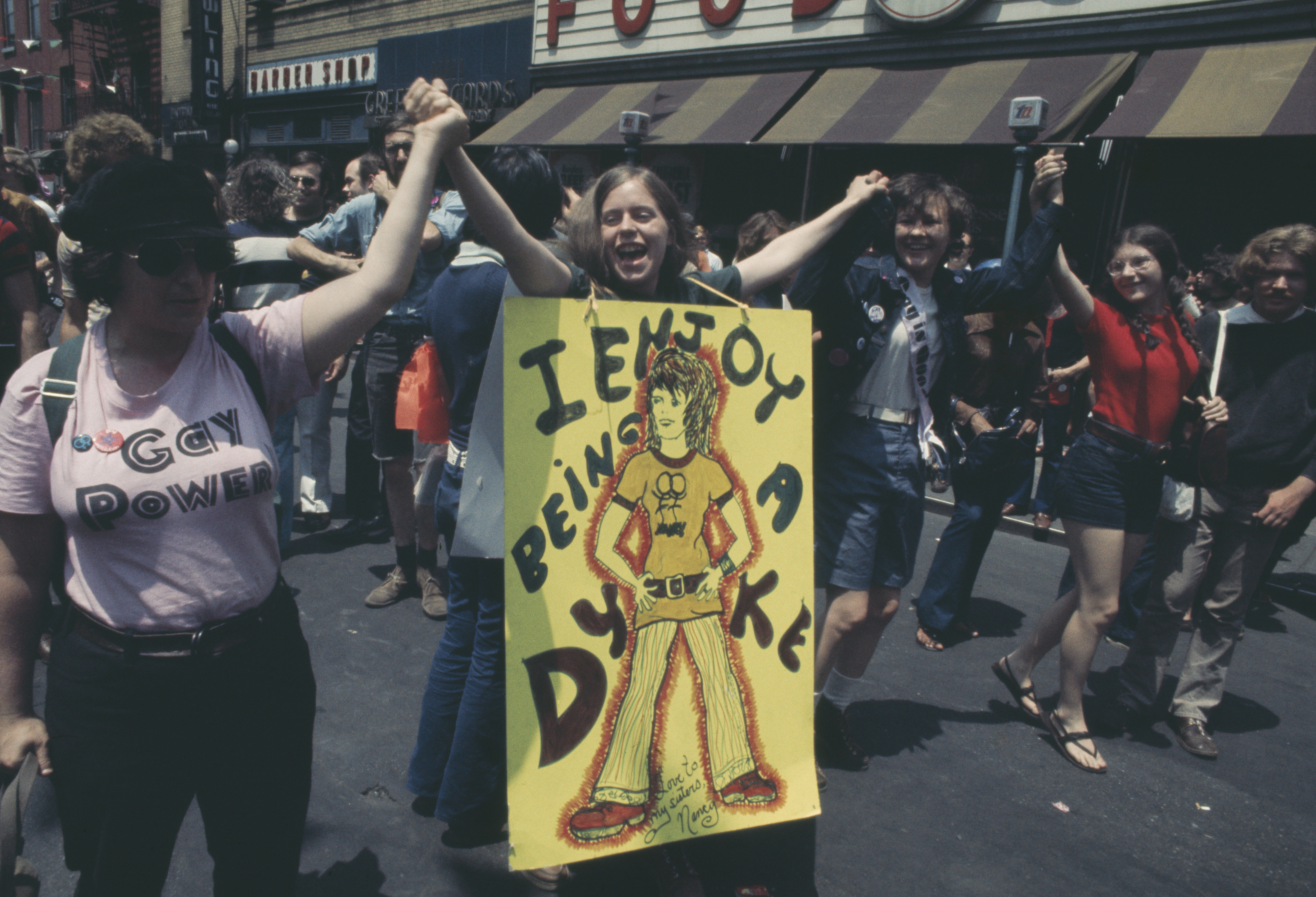A woman holding a placard which reads 'I Enjoy Being a Dyke' during an LGBT parade through New York City on Christopher Street Gay Liberation Day 1971. (Photo by Yigal Mann/Pix/Michael Ochs Archives/Getty Images)