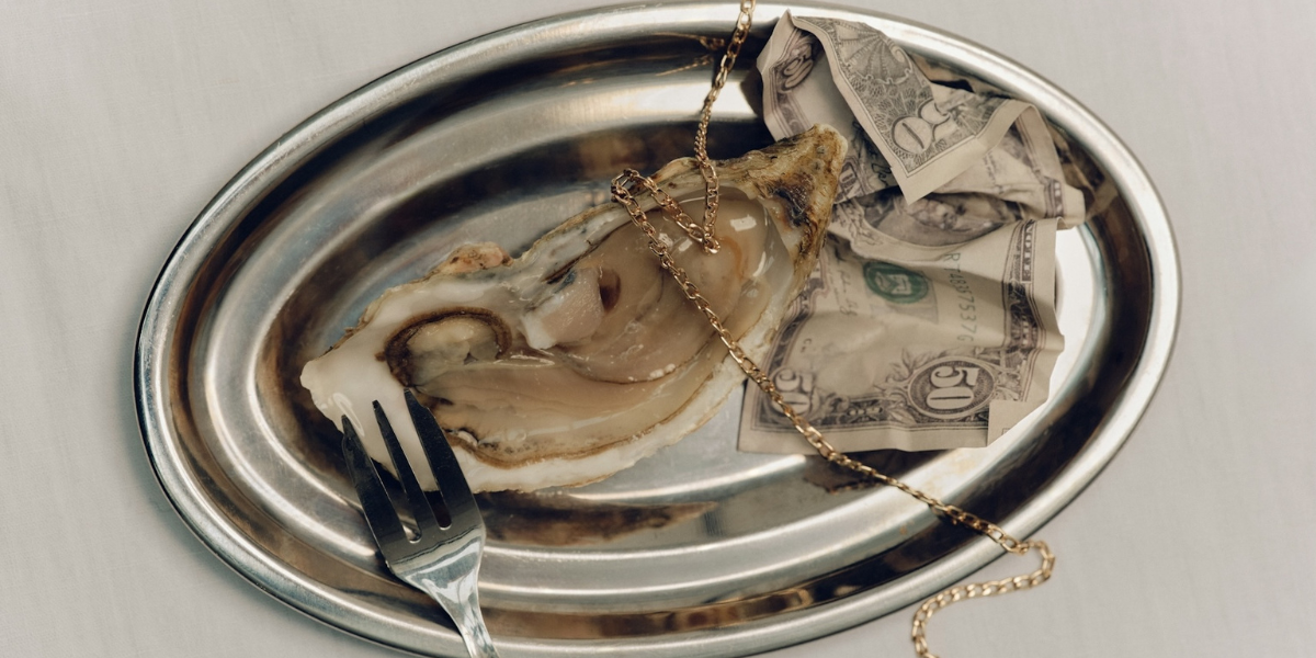 oyster on a plate and a $50 bill and a necklace