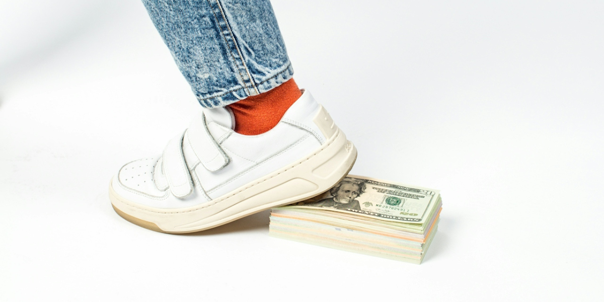 a shoe stepping on a bunch of money
