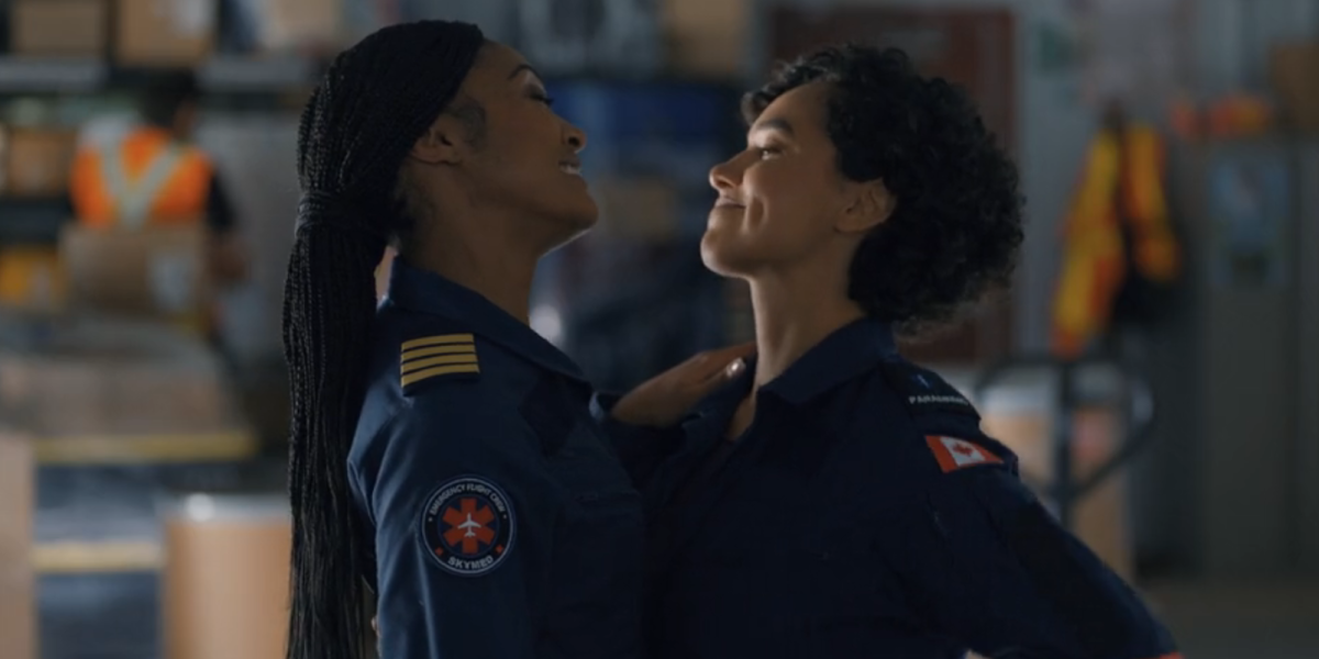 Lexi and Stef from SkyMed smile at each other with their arms around each other's waists.