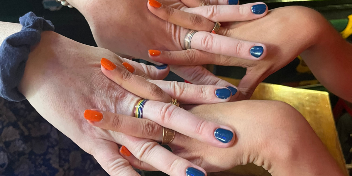 two pairs of hands, painted in the Knicks colors of orange and blue