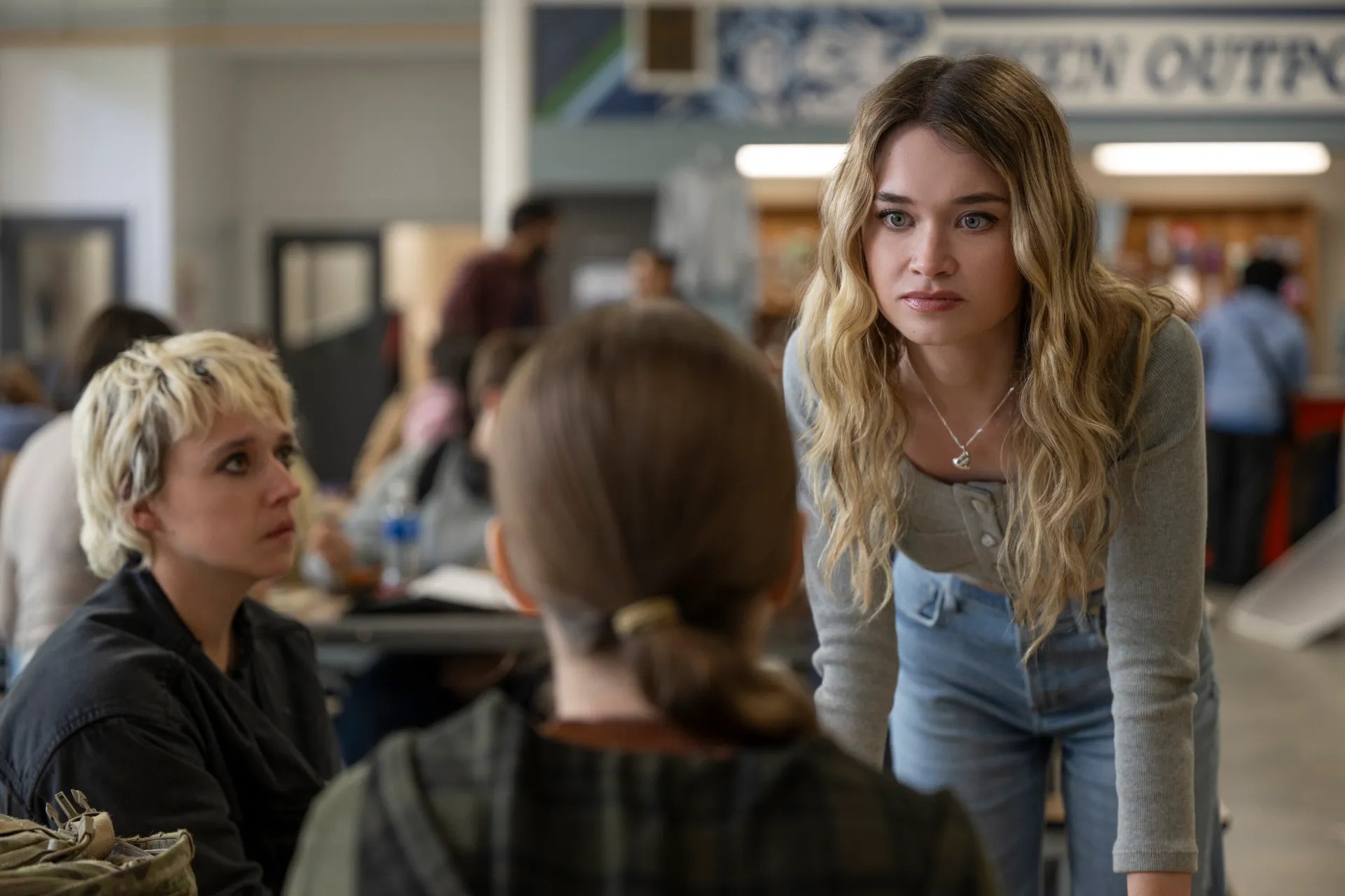 girl leaning over cafeteria table looking upset