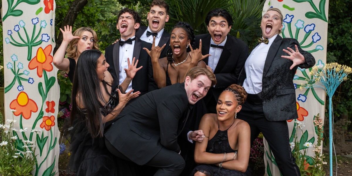 The cast of Heartstopper: Forever poses and makes silly faces for the camera while dressed in black dresses and suits for their senior dance.