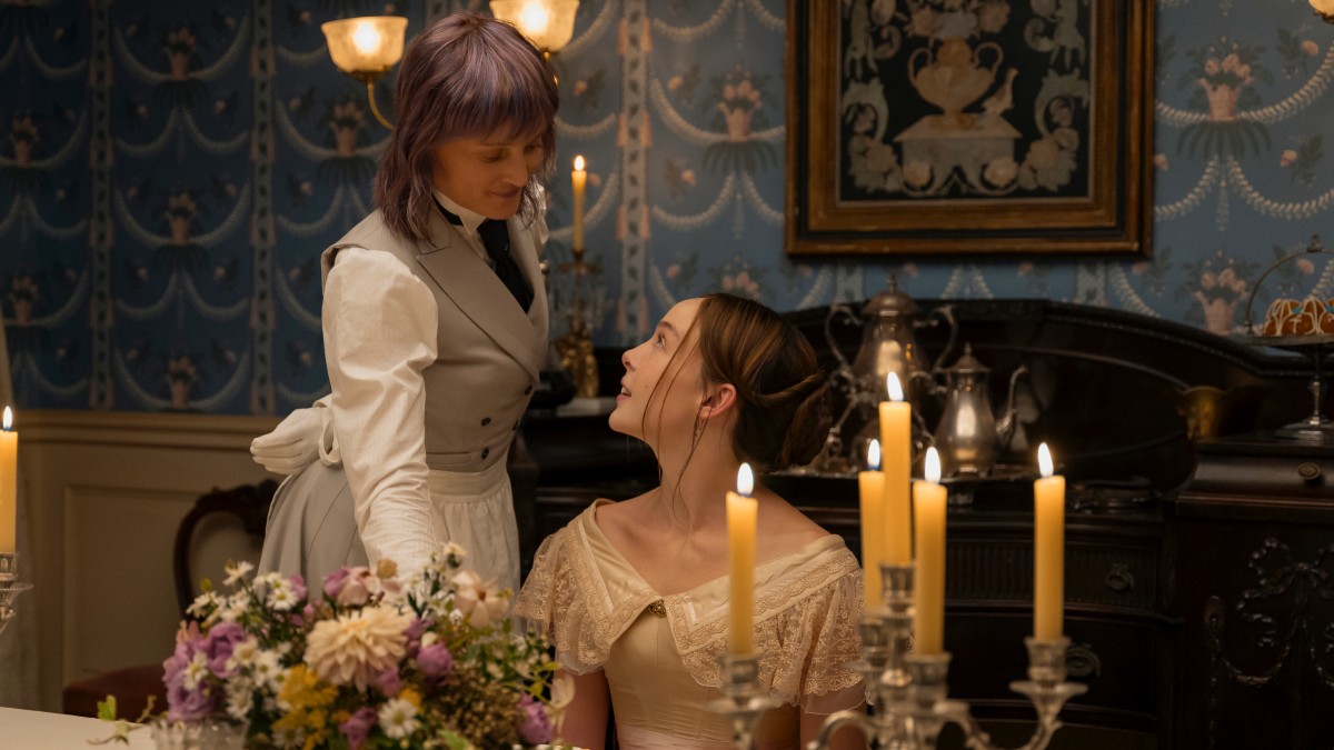 Bridget slash Maggie serving Lizzie over her shoulder, Lizzie looking up at her with a smile.