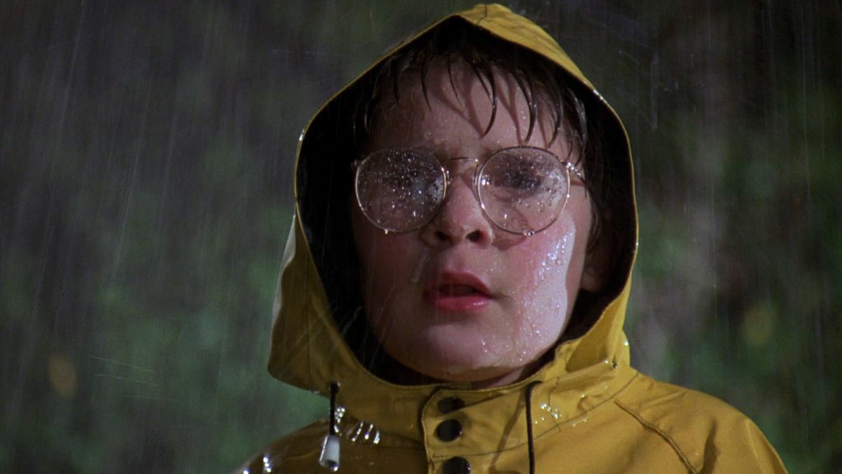 Friday the 13th: A New Beginning, a boy in glasses and a yellow rain coat stands in the rain
